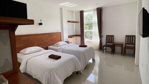 A hotel room with two beds, a TV, a small table, and a chair. - Central Inn (Senggigi)