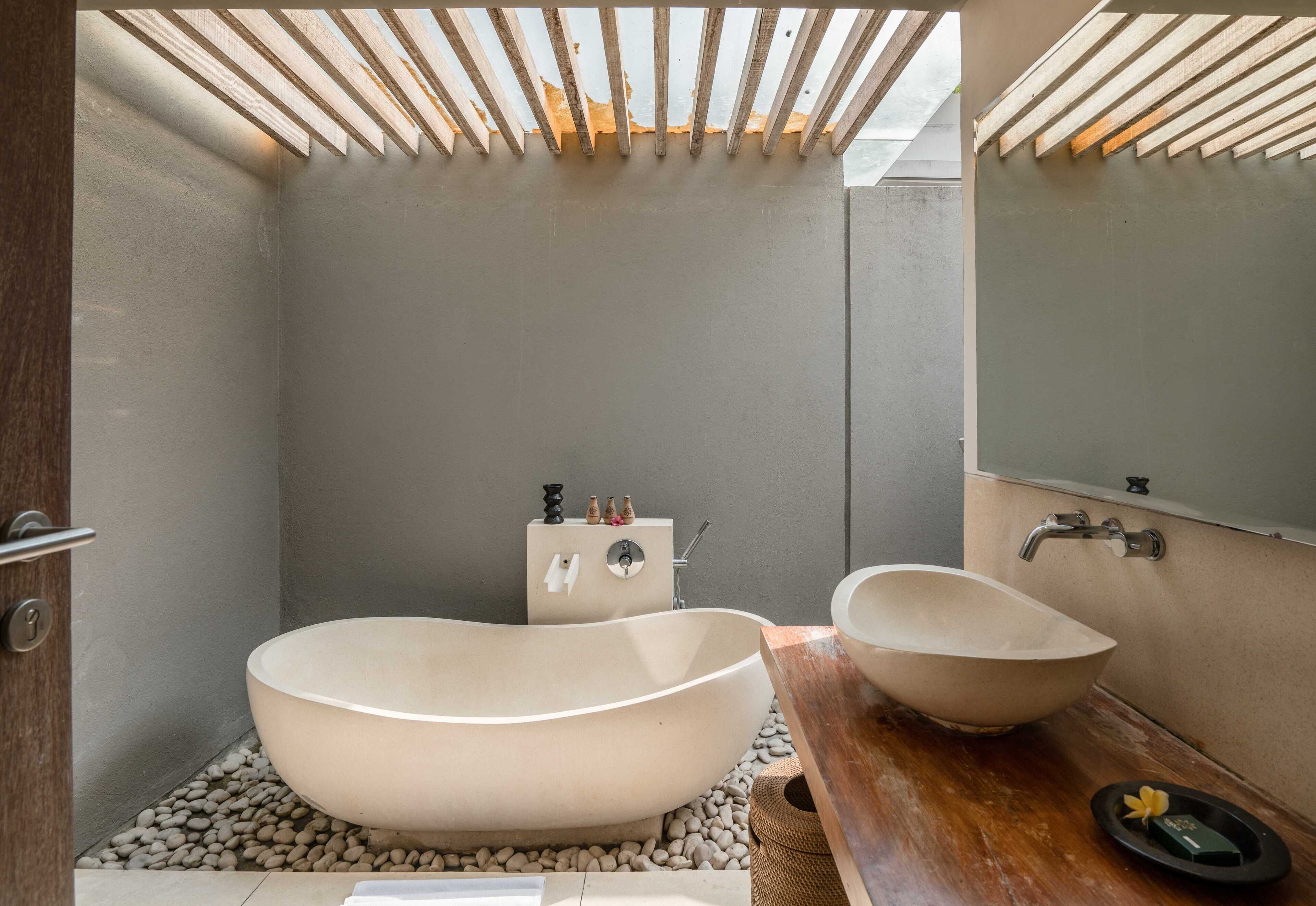 A modern bathroom with a freestanding bathtub, a wooden vanity, and a large mirror.