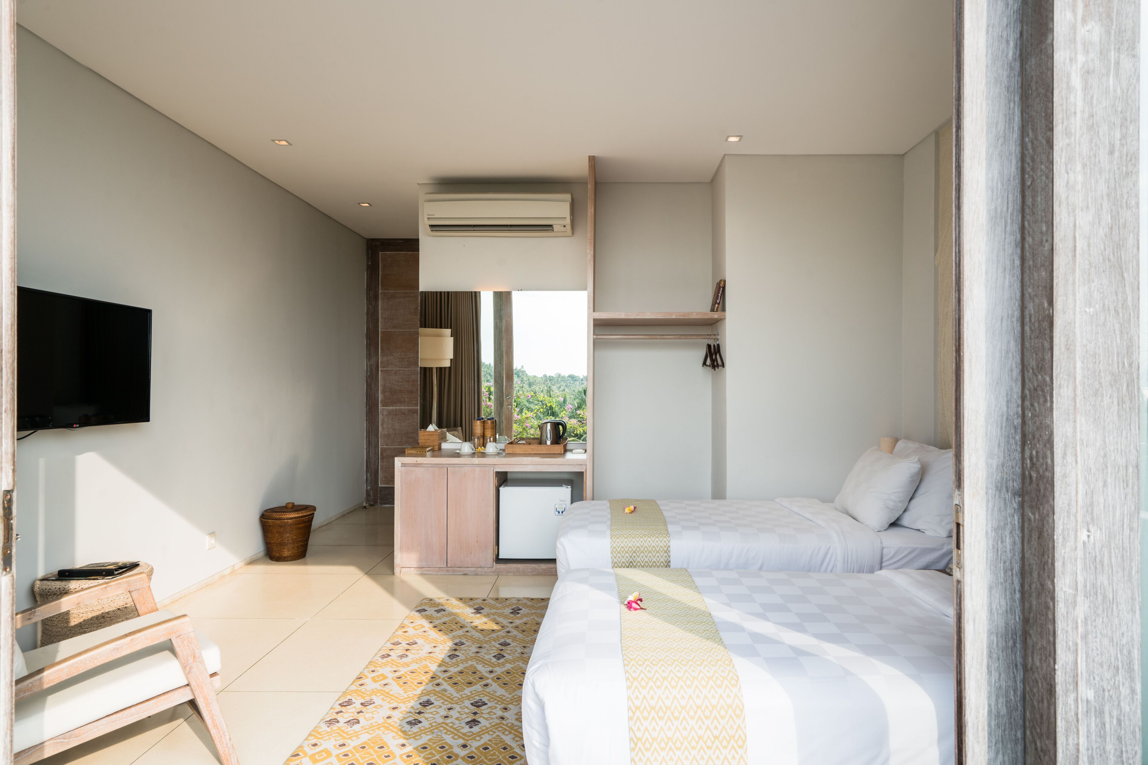 Habitación de hotel con dos camas, un escritorio, un televisor y una ventana con vistas.