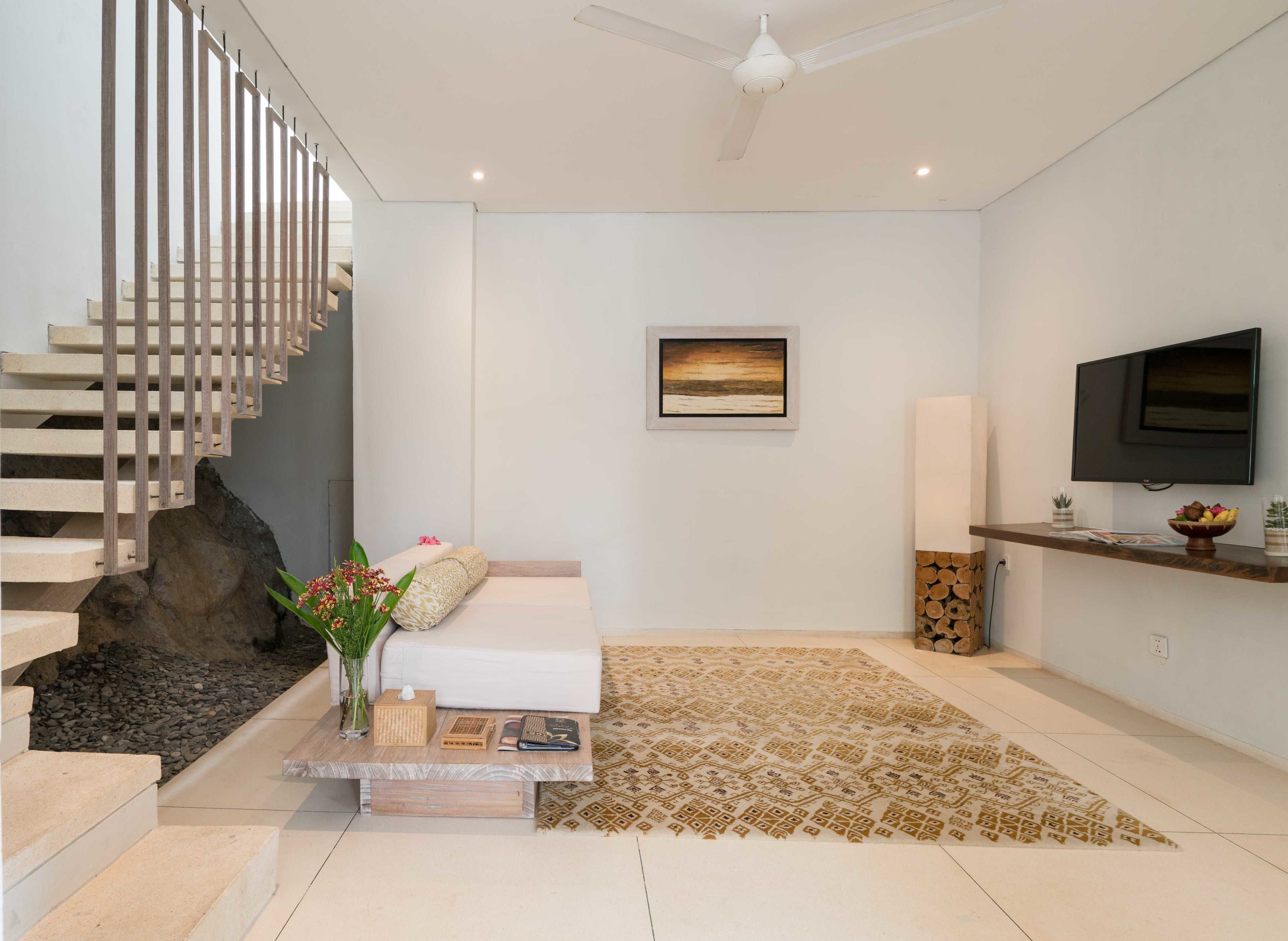 Una sala de estar moderna con una escalera, un televisor de pantalla plana, un cuadro y un tapete decorativo.