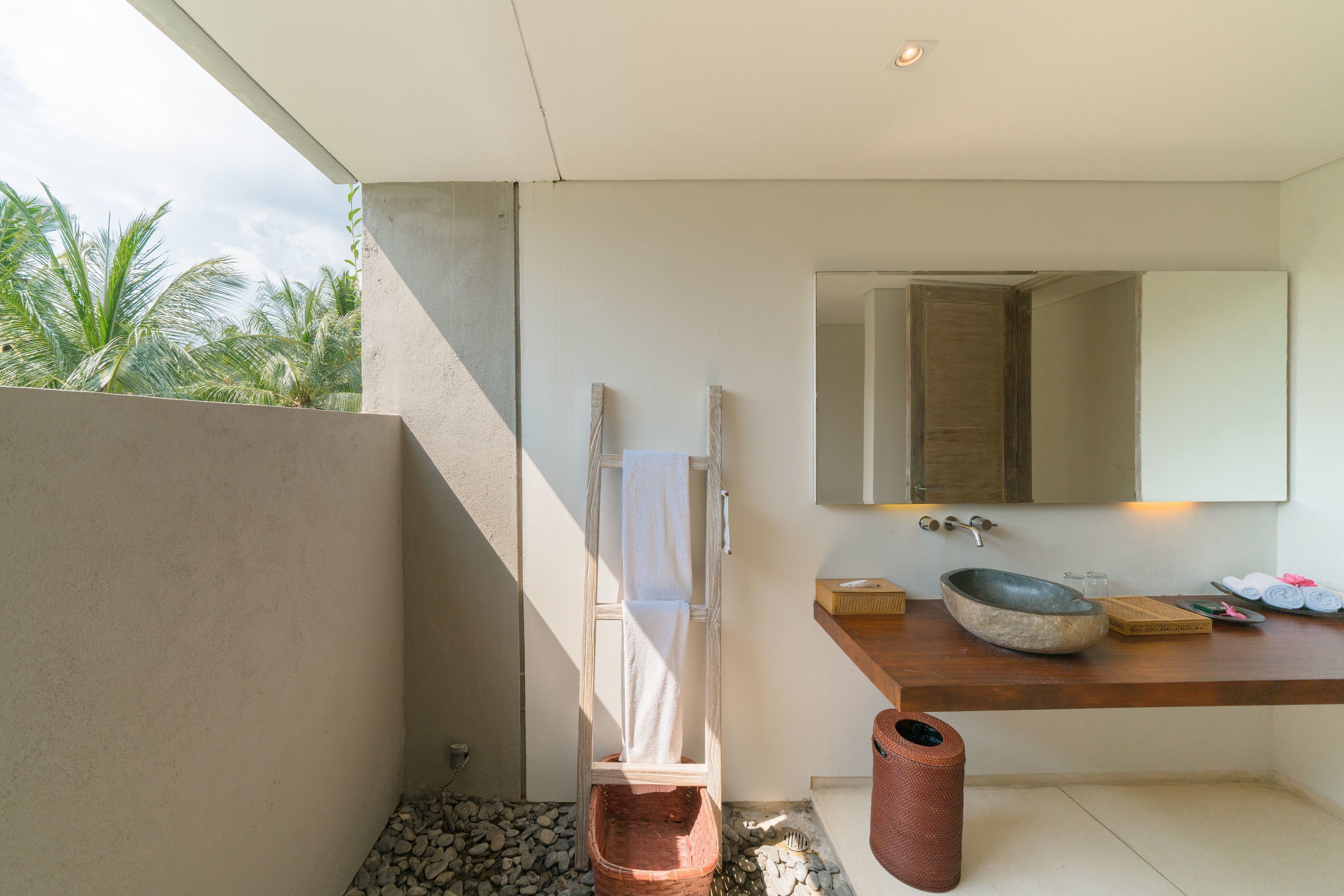 Un baño moderno con lavamanos de piedra, encimera de madera y un espejo grande.