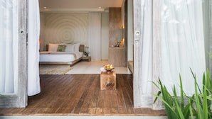 Une chambre à coucher avec un grand lit, une table de chevet sur laquelle se trouve un panier de fruits, et une tête de lit en bois.