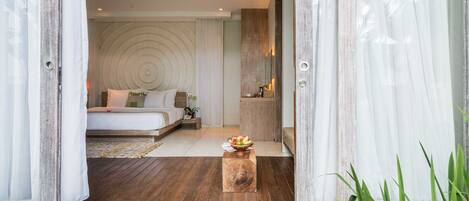 Un dormitorio con una cama grande, una mesita de noche con un cuenco de fruta y un cabecero de madera.