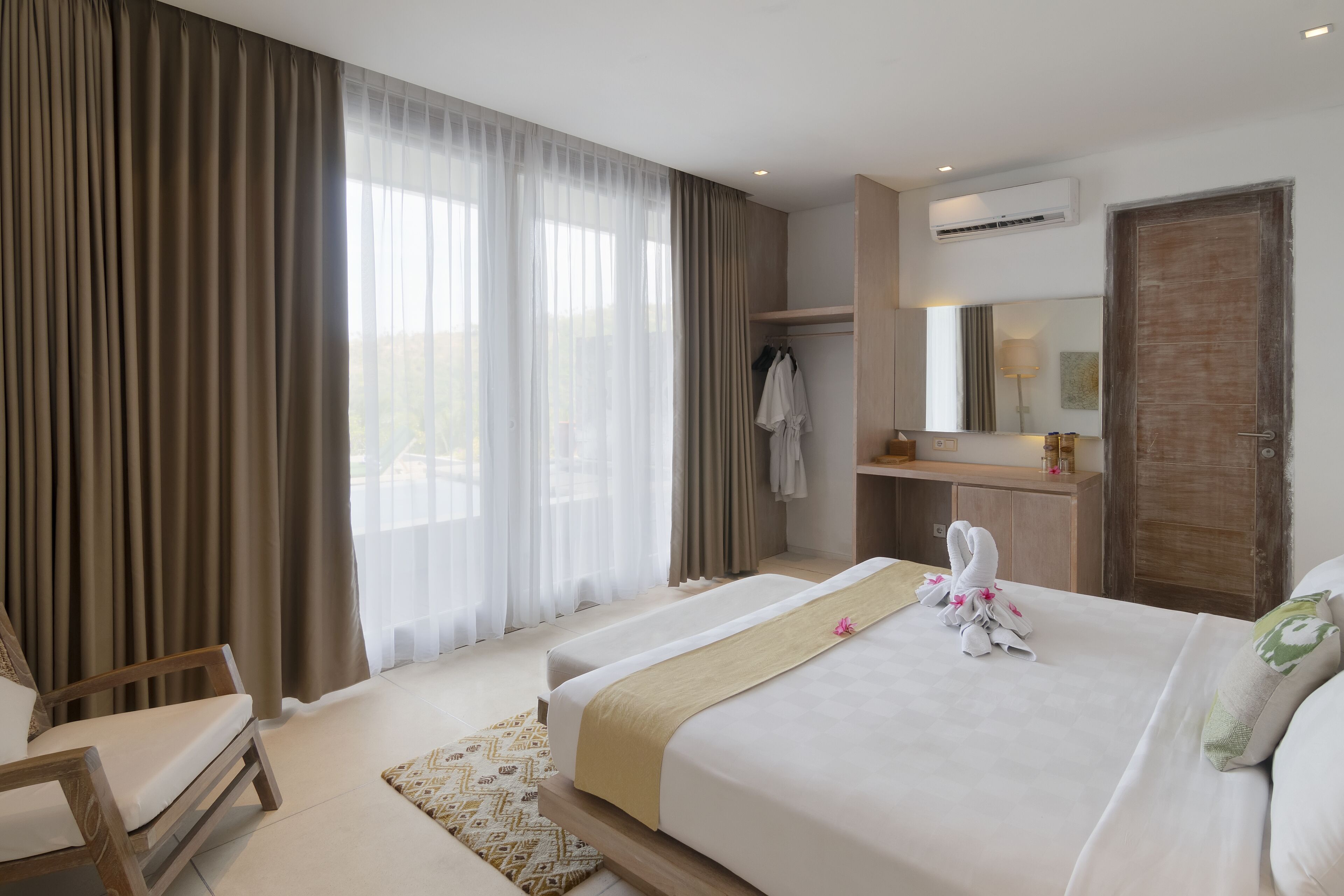 Een hotelkamer met een groot bed, een stoel, een bureau en een garderobe.
