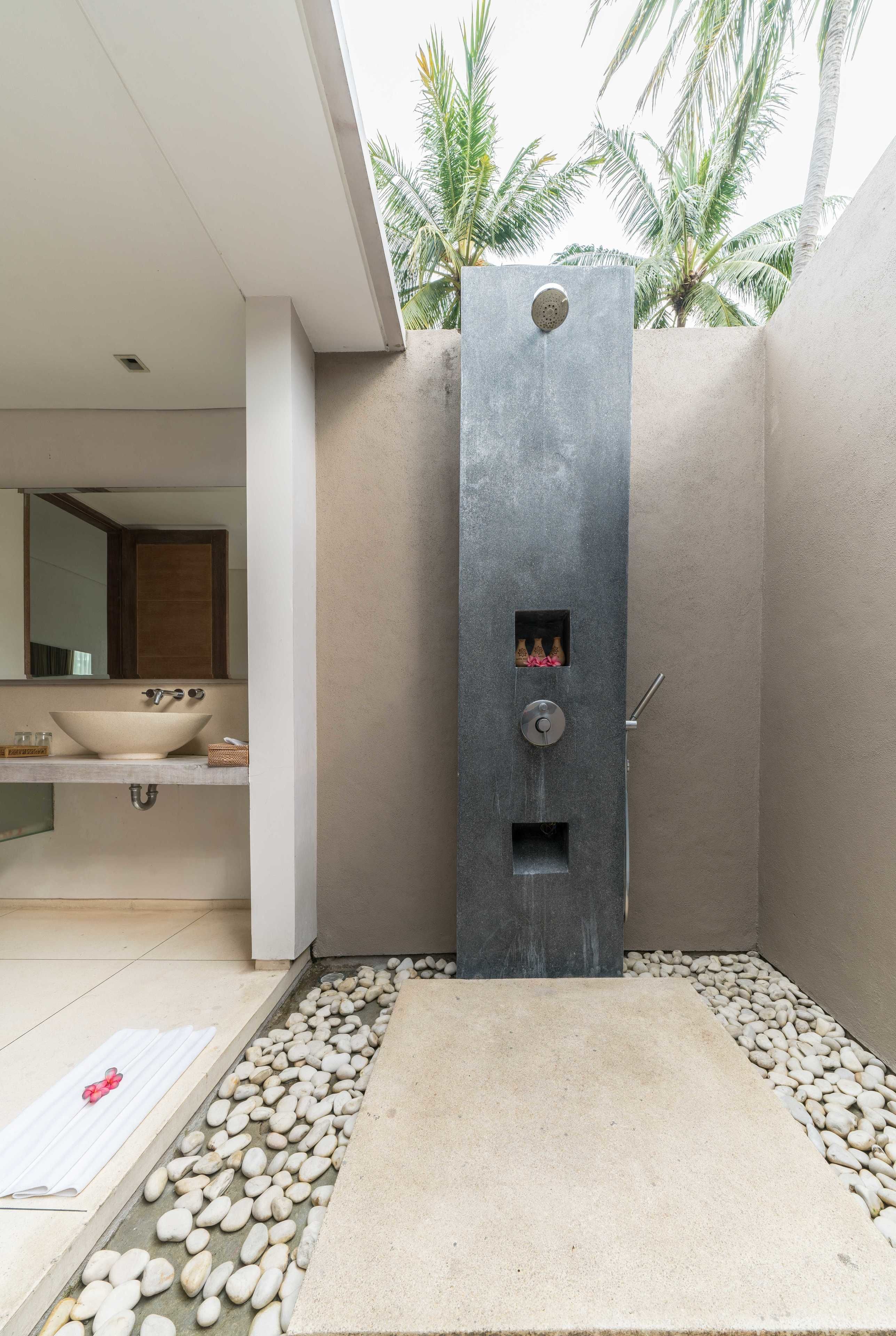 A modern bathroom with a large sink, a shower with a control panel, and a pebble-tiled floor.