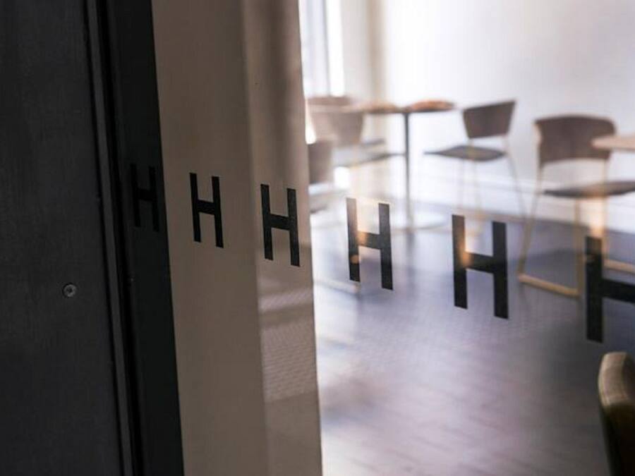 Una puerta con las letras 'HHHHH', que da a una habitación de diseño moderno y minimalista, con pared de ladrillo y suelo de madera.