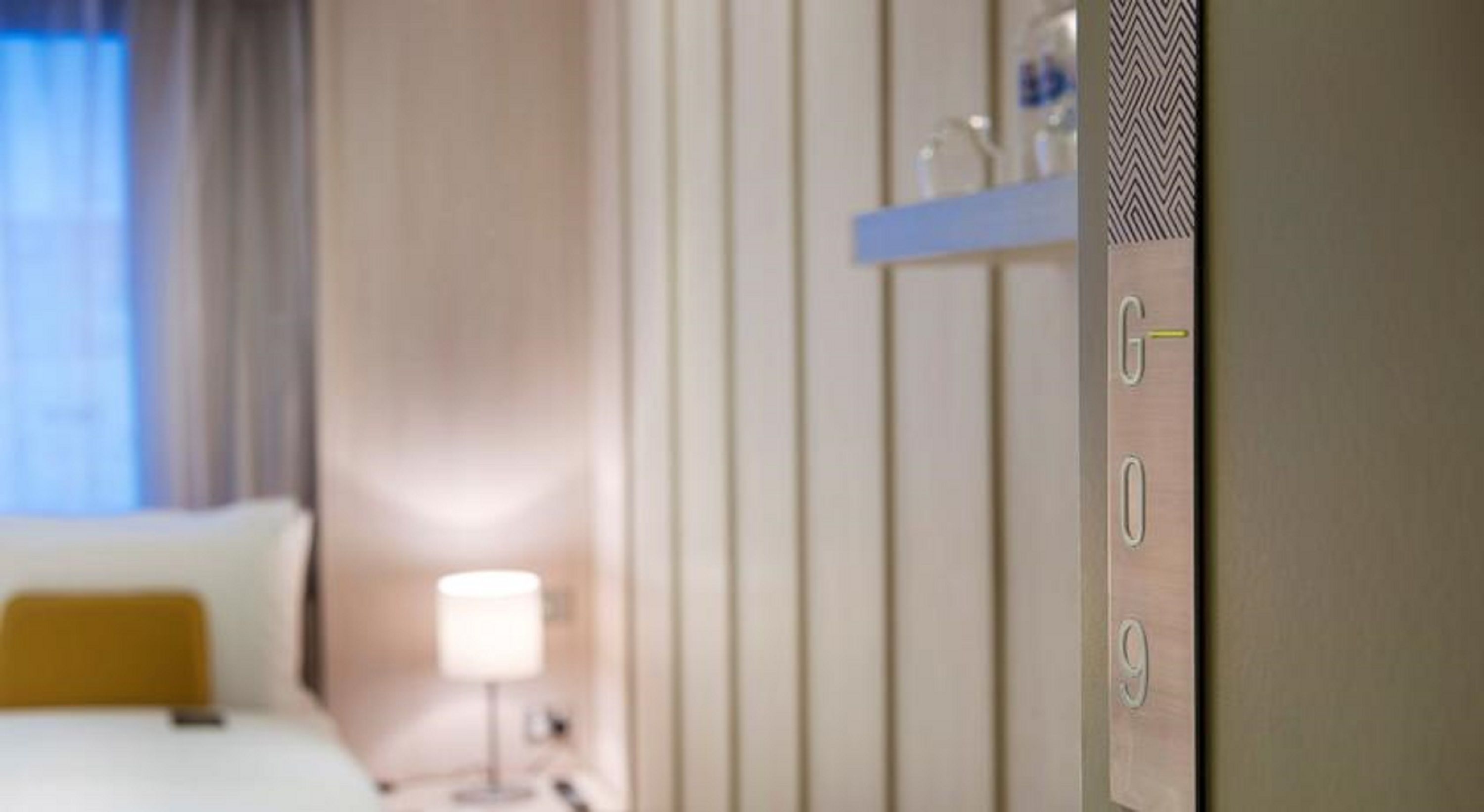 Una habitació d'hotel amb llit, una tauleta de nit i una làmpada.