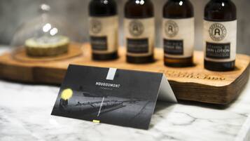 A display of four brown glass bottles with labels, a wooden tray, and a card with the text "HOUGOUMONT FREMANTLE" on a marble surface.