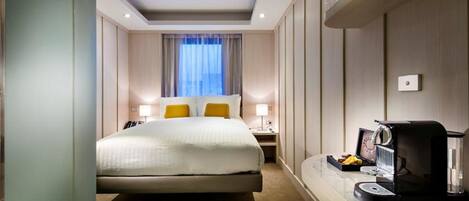 A hotel room with a bed, bedside lamps, a coffee machine, and a window with curtains.