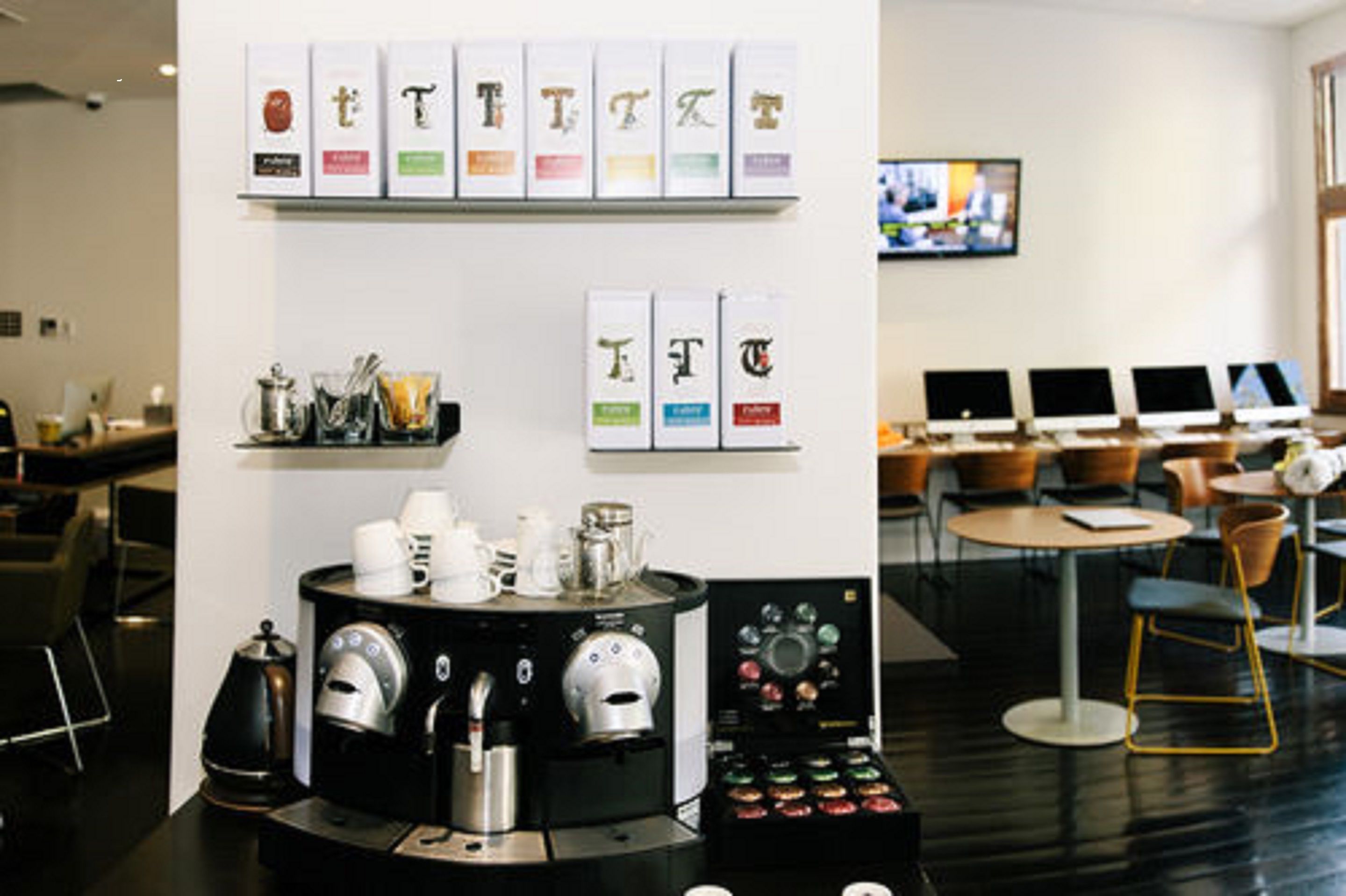 A modern coffee shop with a coffee machine, cups, and a display of coffee beans.