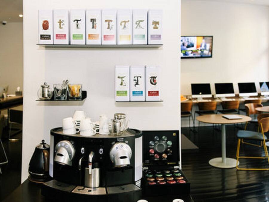 A modern coffee shop with a coffee machine, cups, and a display of coffee beans.