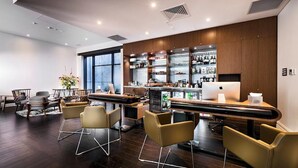 Un moderno vestíbulo de hotel con zona de bar, asientos y un amplio ventanal que ofrece vistas.