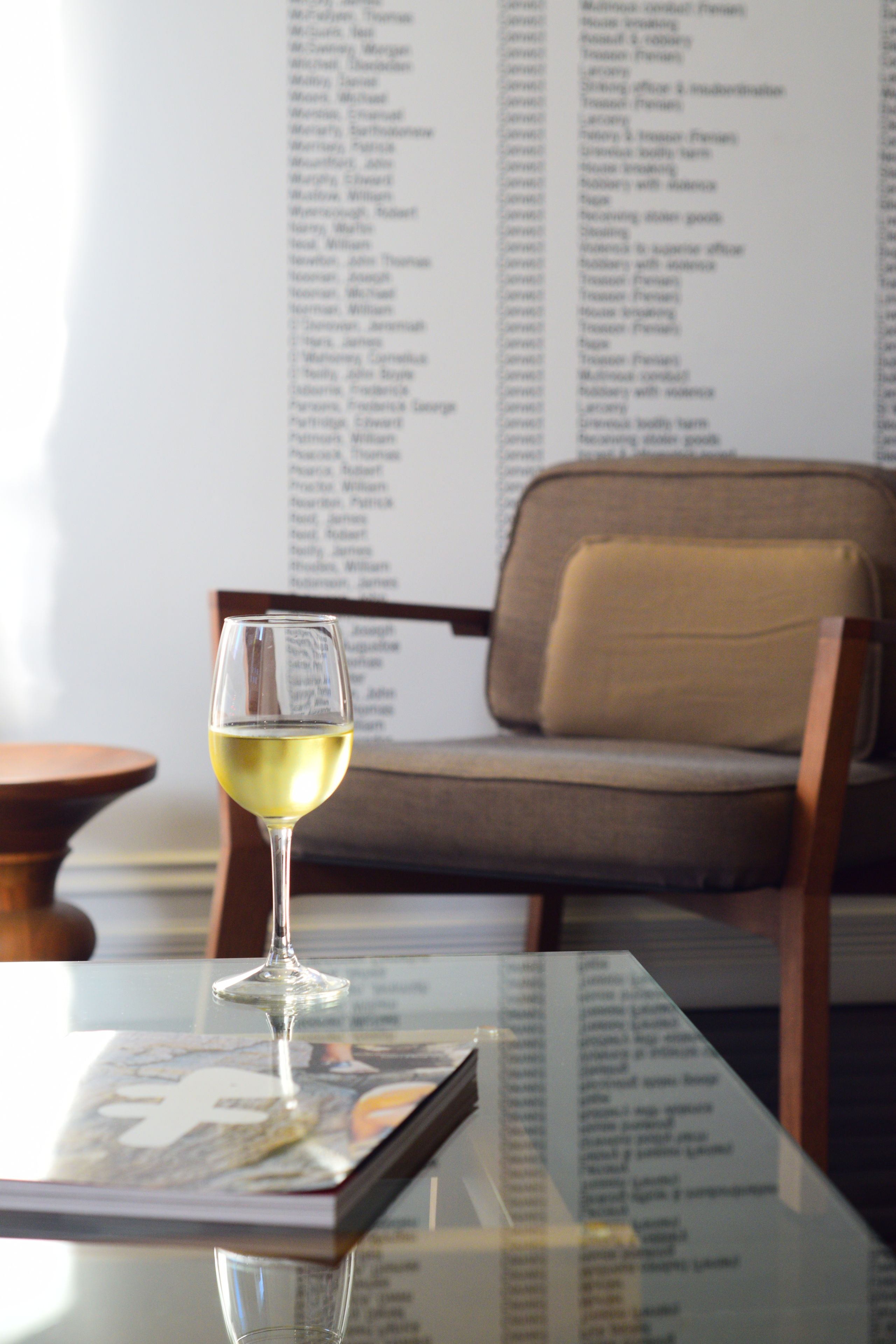 Una copa de vino blanco sobre una mesa, con un menú de fondo.