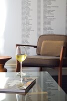 Una copa de vino blanco sobre una mesa, con un menú de fondo.