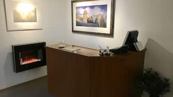 A reception desk with a fireplace, framed artwork, and a potted plant.