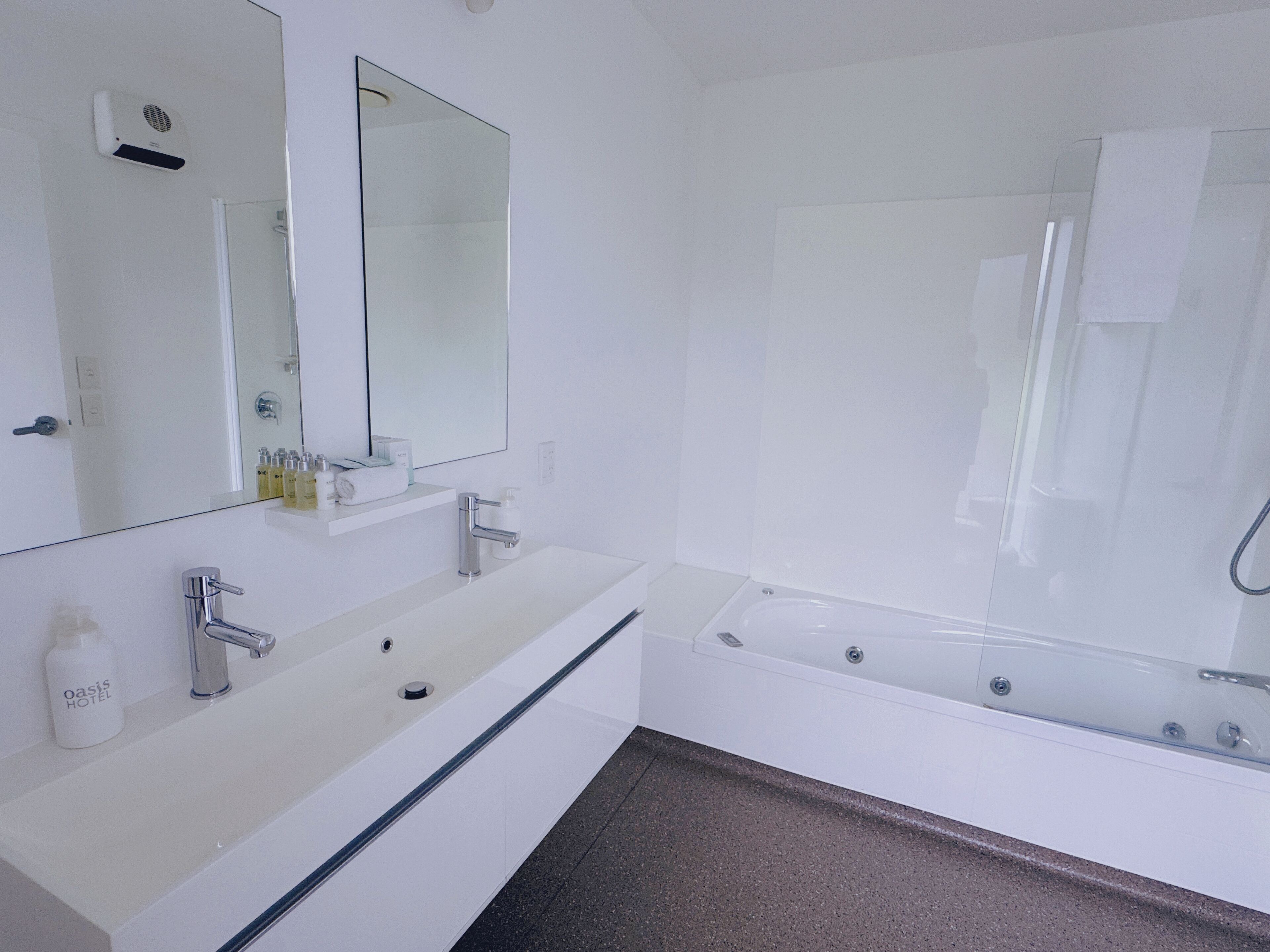 Un baño moderno con un lavamanos blanco, un espejo grande y una bañera.