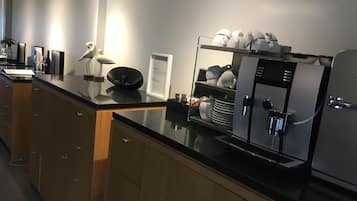 Una cocina moderna con encimera negra, armarios de madera y una cafetera integrada.