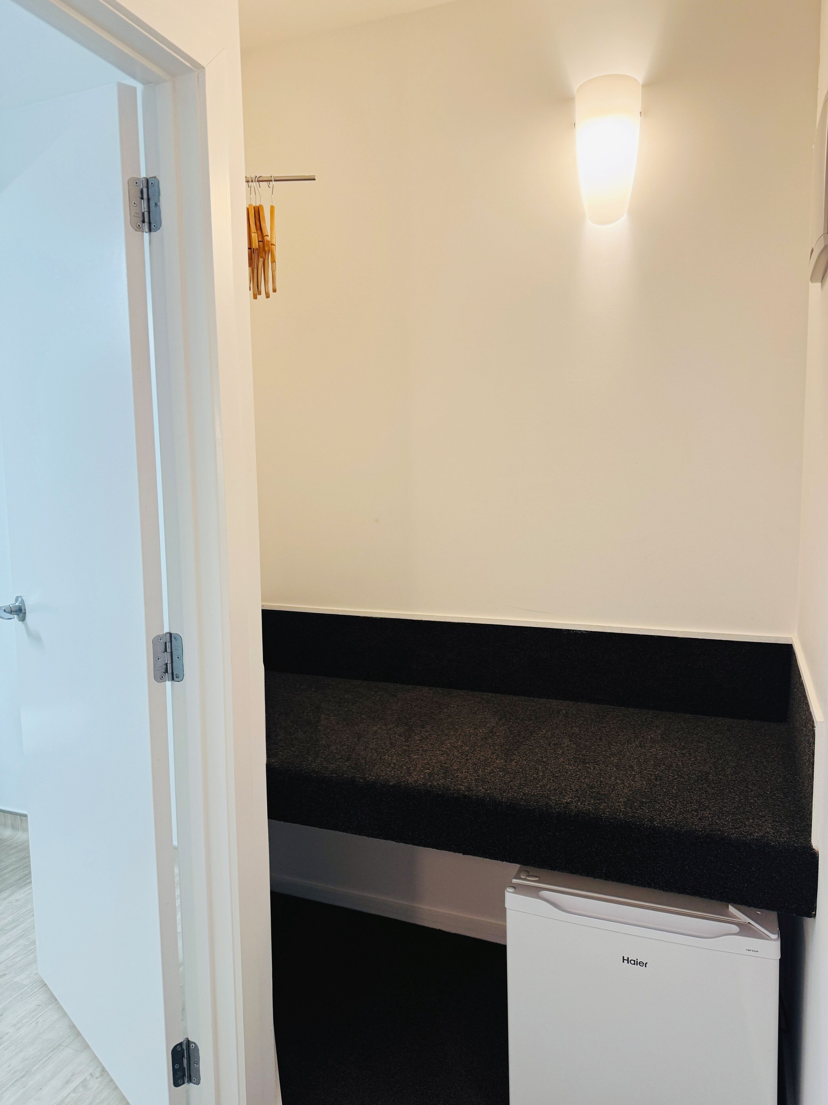 Une pièce avec une porte blanche, un comptoir noir et un appareil électroménager blanc portant l’inscription « Haier ».