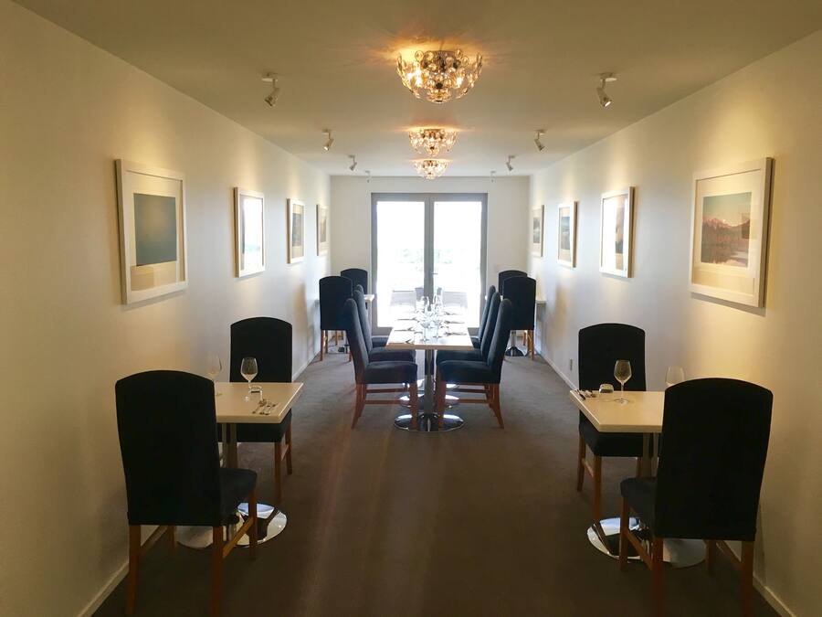 A dining area with a long table, black chairs, and framed pictures on the walls.