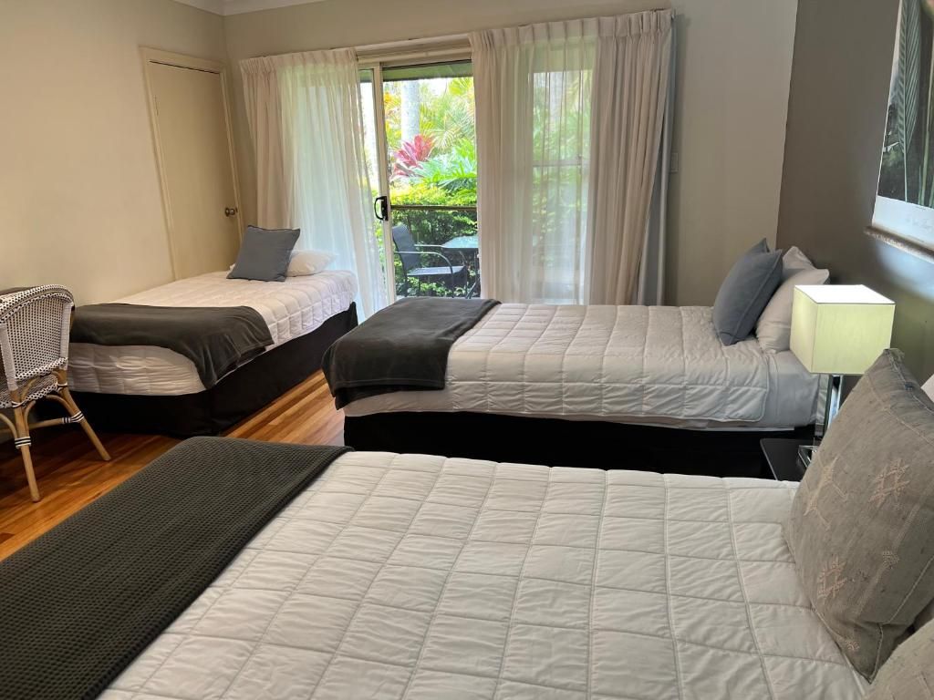 Une chambre d’hôtel avec deux lits, une chaise, une table et une fenêtre avec des rideaux.