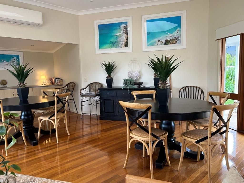 A dining area with a round table and chairs, a kitchen in the background, and two framed pictures on the wall.