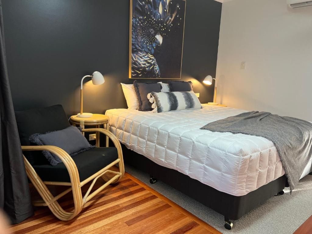 A bedroom with a bed, two bedside lamps, a chair, and a wall-mounted artwork.