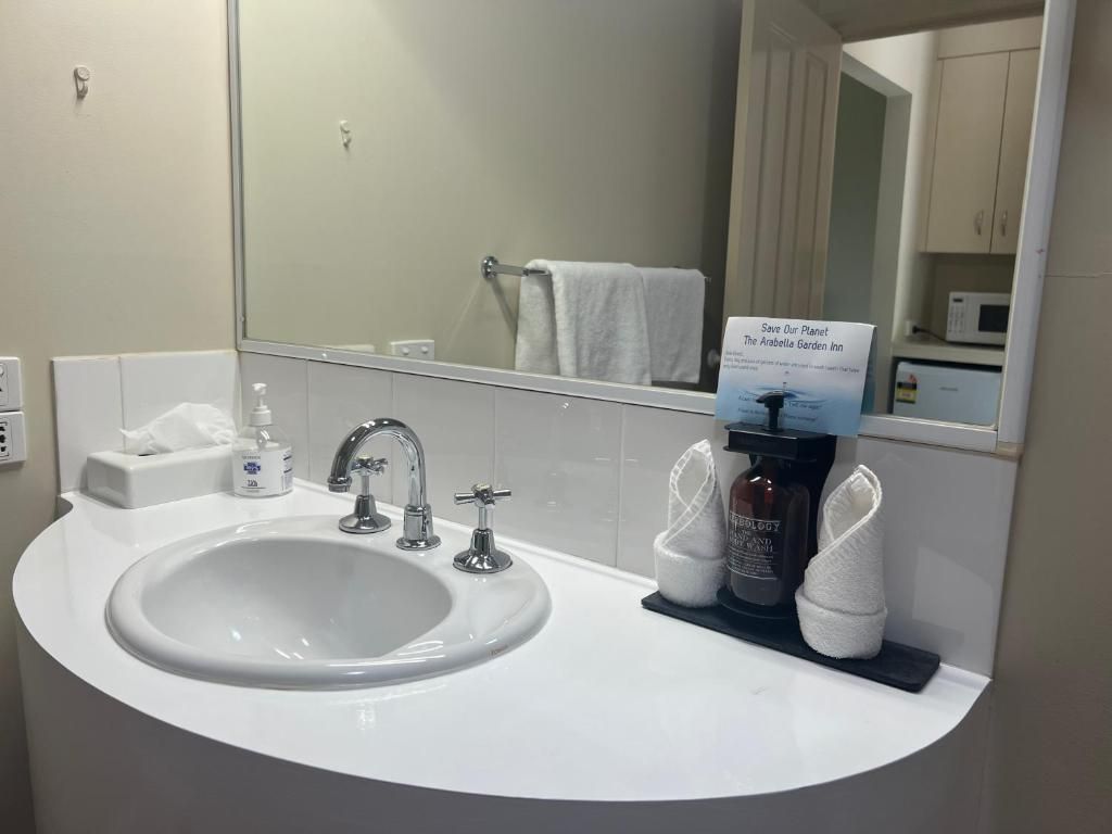 Ein Badezimmer mit einem weißen Waschbecken, einem Spiegel und einem Schild zum Thema Umweltschutz.