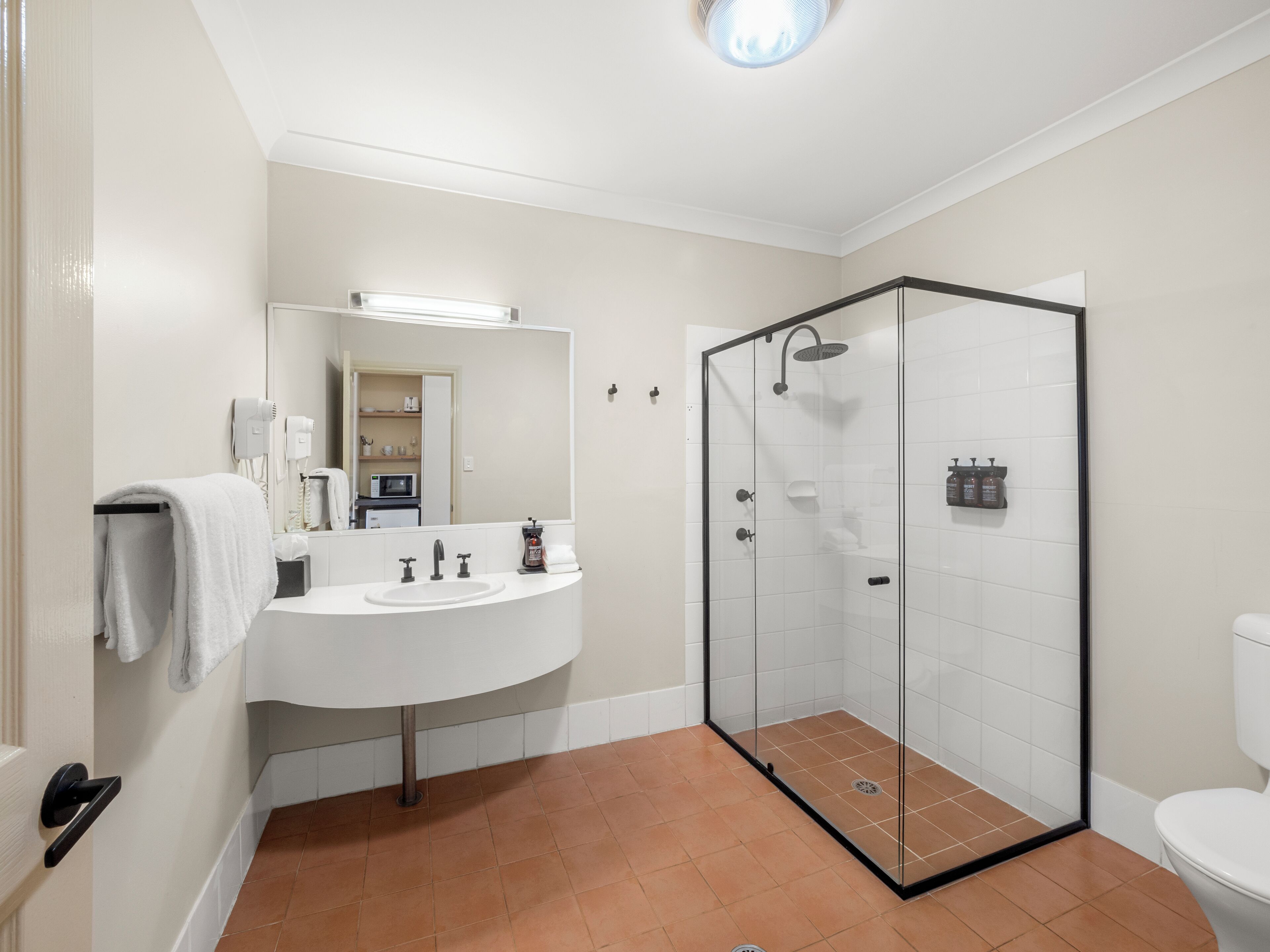 A bathroom with a glass-enclosed shower, a white sink, and a toilet.