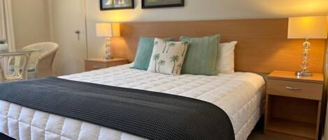 Una habitación de hotel con una cama, dos mesitas de noche, una silla y decoración en la pared.