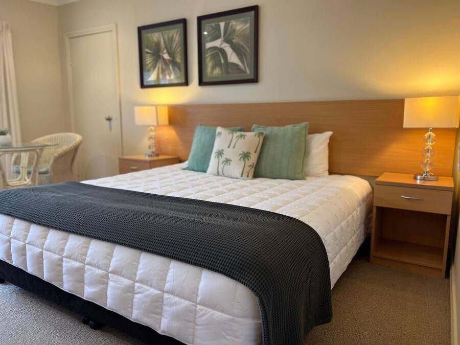 Una habitación de hotel con una cama, dos mesitas de noche, una silla y decoración en la pared.