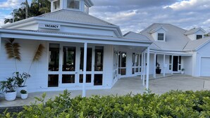 A white building with a 'VACANCY' sign, large windows, and a covered porch area. - Arabella Garden Inn Motel (Wollongbar)