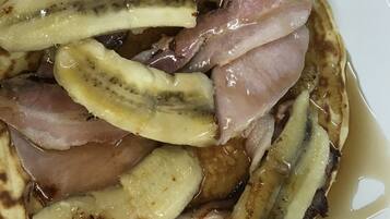 A plate of pancakes with banana slices and bacon.