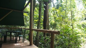 An outdoor wooden deck with chairs and a table, surrounded by dense tropical foliage. - Daintree Crocodylus (Cow Bay)