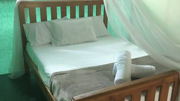 Un lit avec un cadre en bois, des draps blancs et une couverture grise.