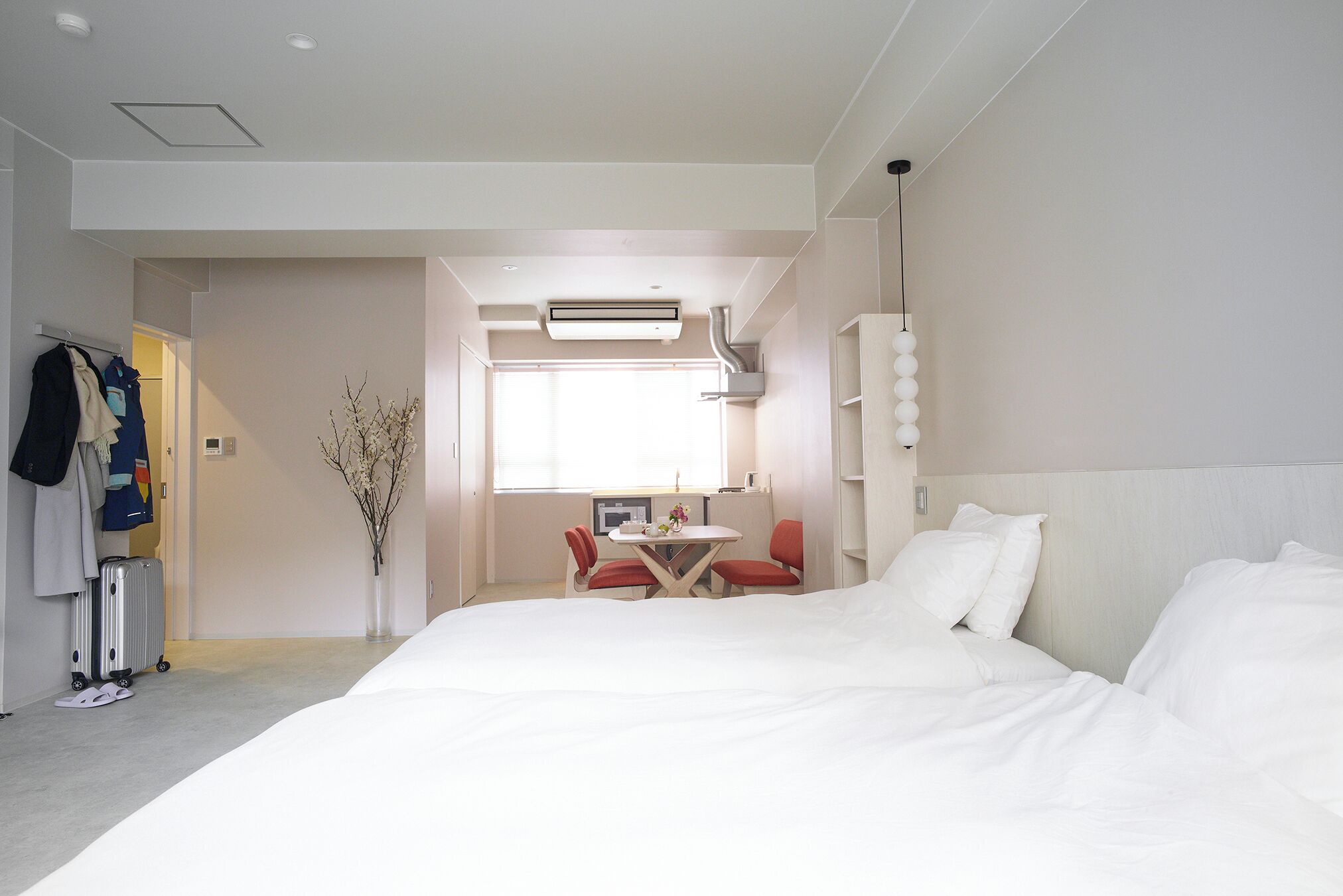 A hotel room with a large bed, a desk with two chairs, and a window providing natural light.