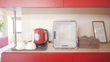 A kitchenette with a red coffee maker, a transparent water dispenser, and a framed menu on the counter.