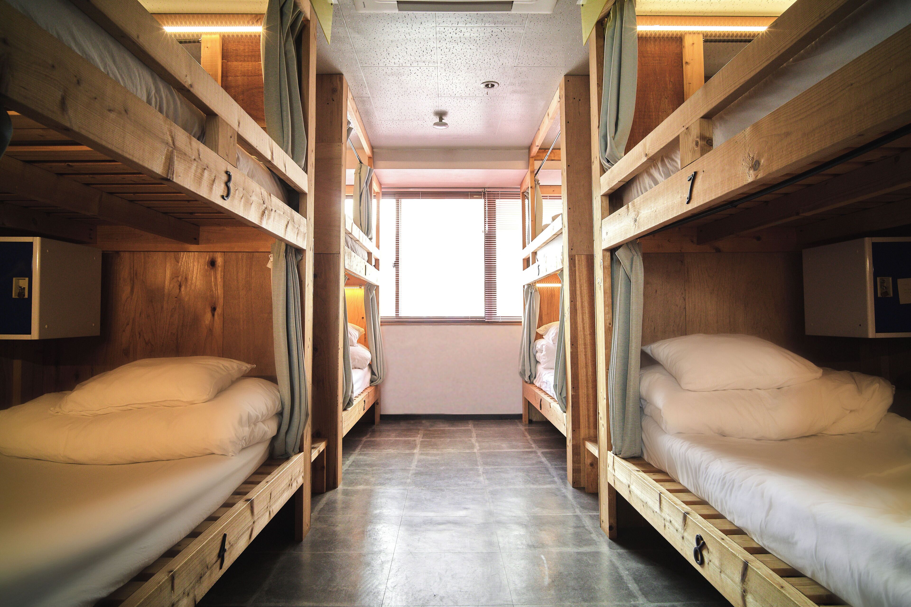 A narrow corridor with bunk beds on either side, wooden walls, and a window at the end.