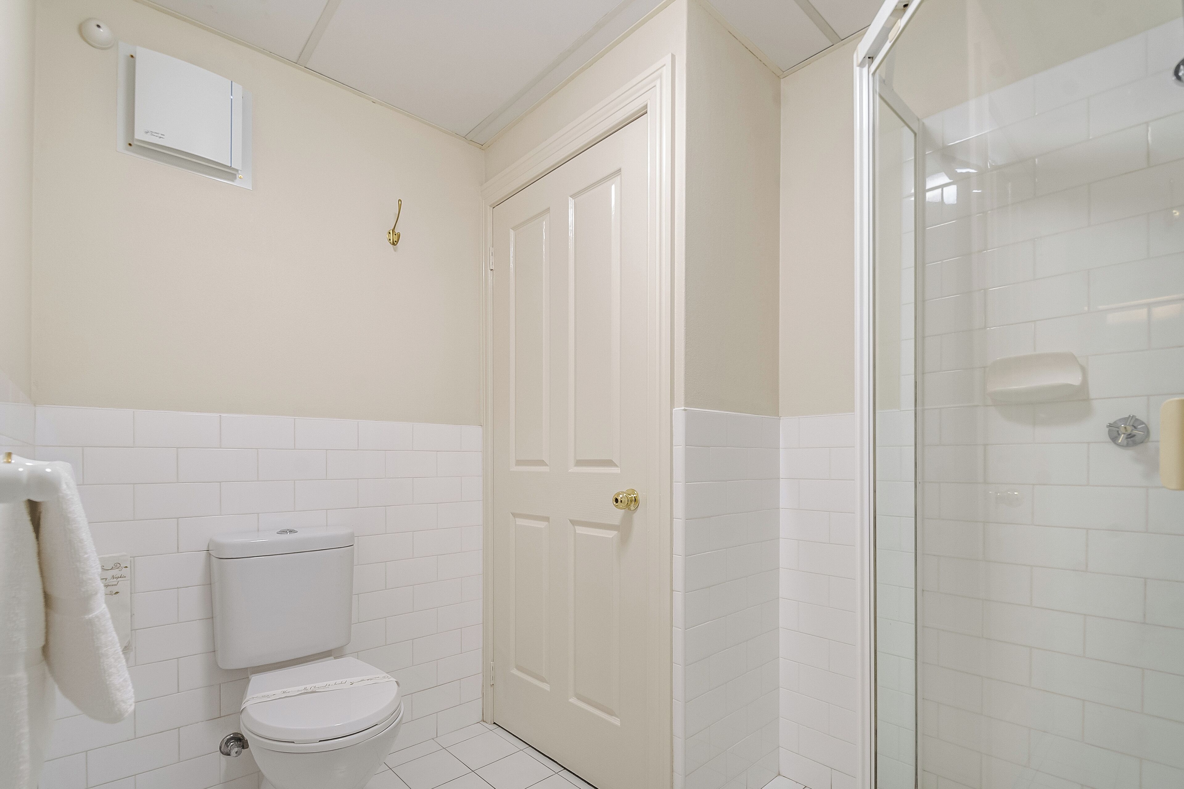 Un baño con inodoro, ducha y una puerta blanca.