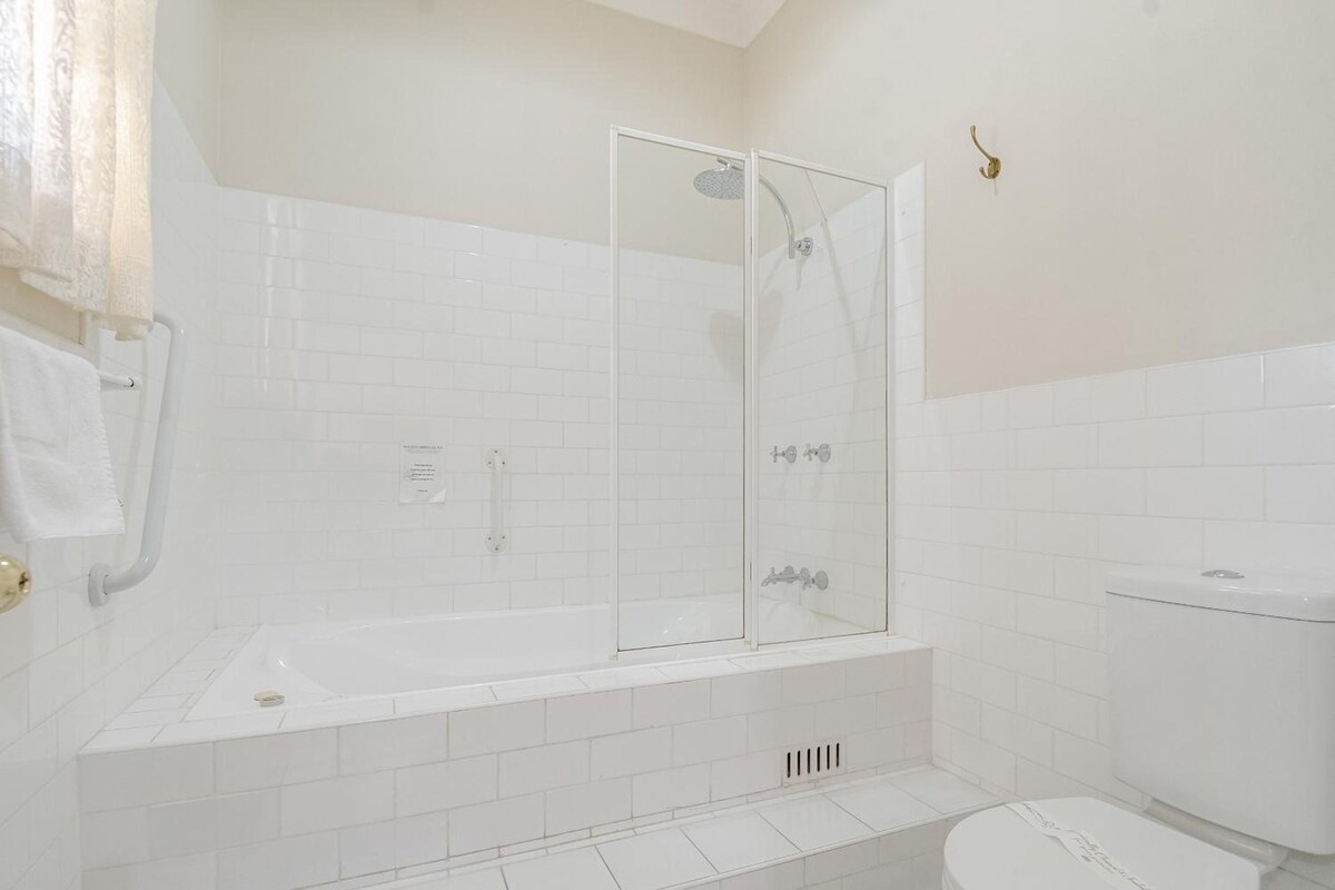 A bathroom with a glass-enclosed shower, a white toilet, and a bathtub.