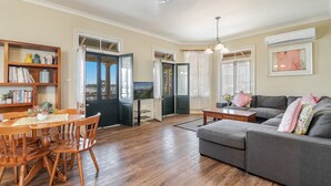 A living room with a wooden dining table, chairs, a gray sofa, and a bookshelf. - Ballina Heritage Inn (Ballina)