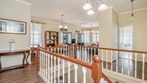 A spacious living room with a wooden staircase, a bookshelf, and a dining area. - Ballina Heritage Inn (Ballina)