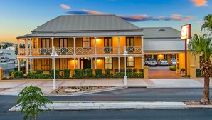 A two-story hotel with a balcony, a covered entrance, and a parking area. - Ballina Heritage Inn (Ballina)