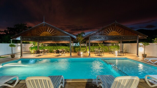 A swimming pool with lounge chairs and covered seating areas, surrounded by greenery. - Riverra Inn Langkawi (Langkawi)