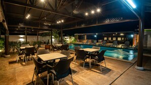 An outdoor pool area with lounge chairs and tables, surrounded by potted plants and a covered seating area. - Riverra Inn Langkawi (Langkawi)