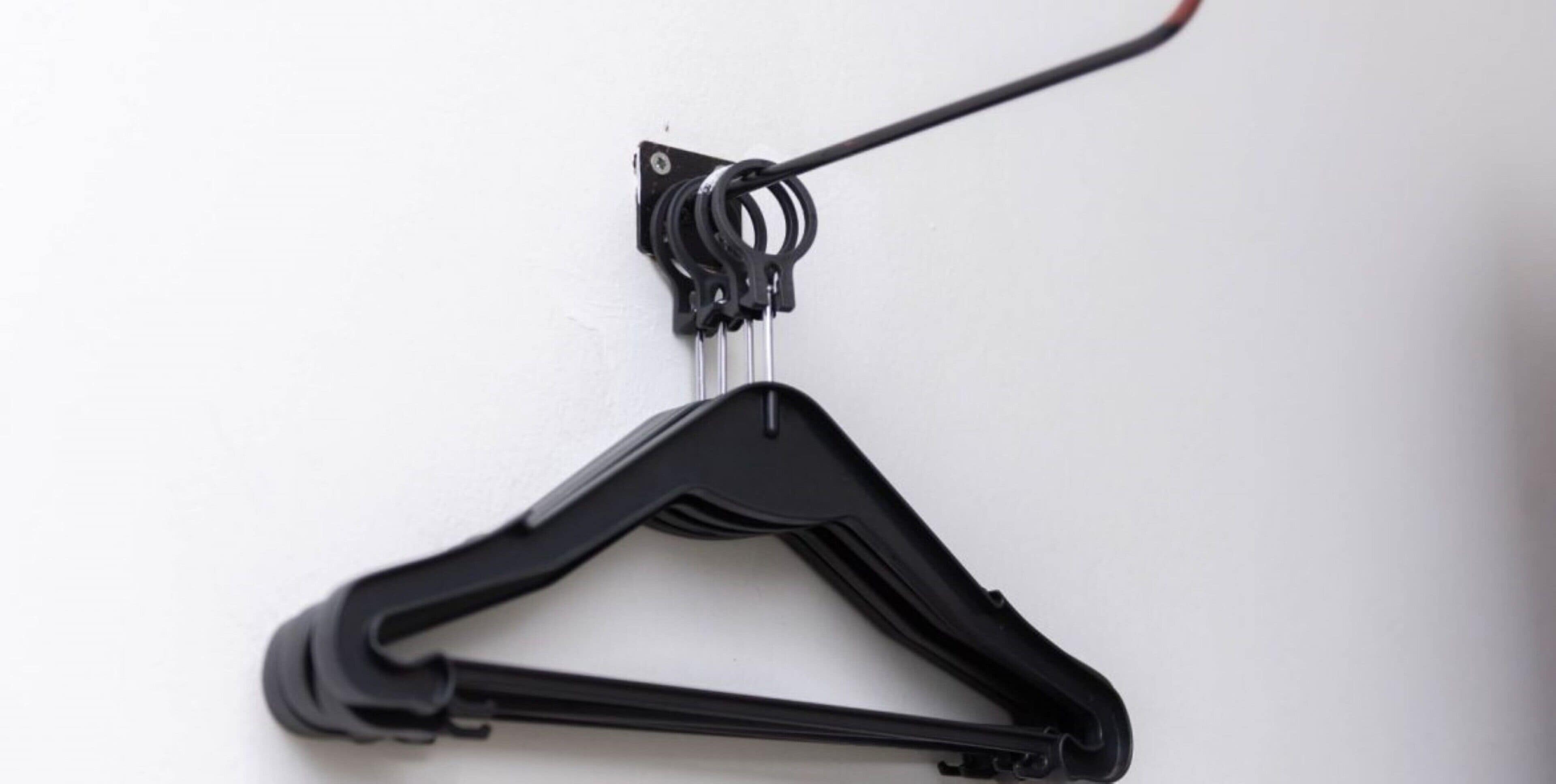 Un cintre noir fixé sur un mur blanc.