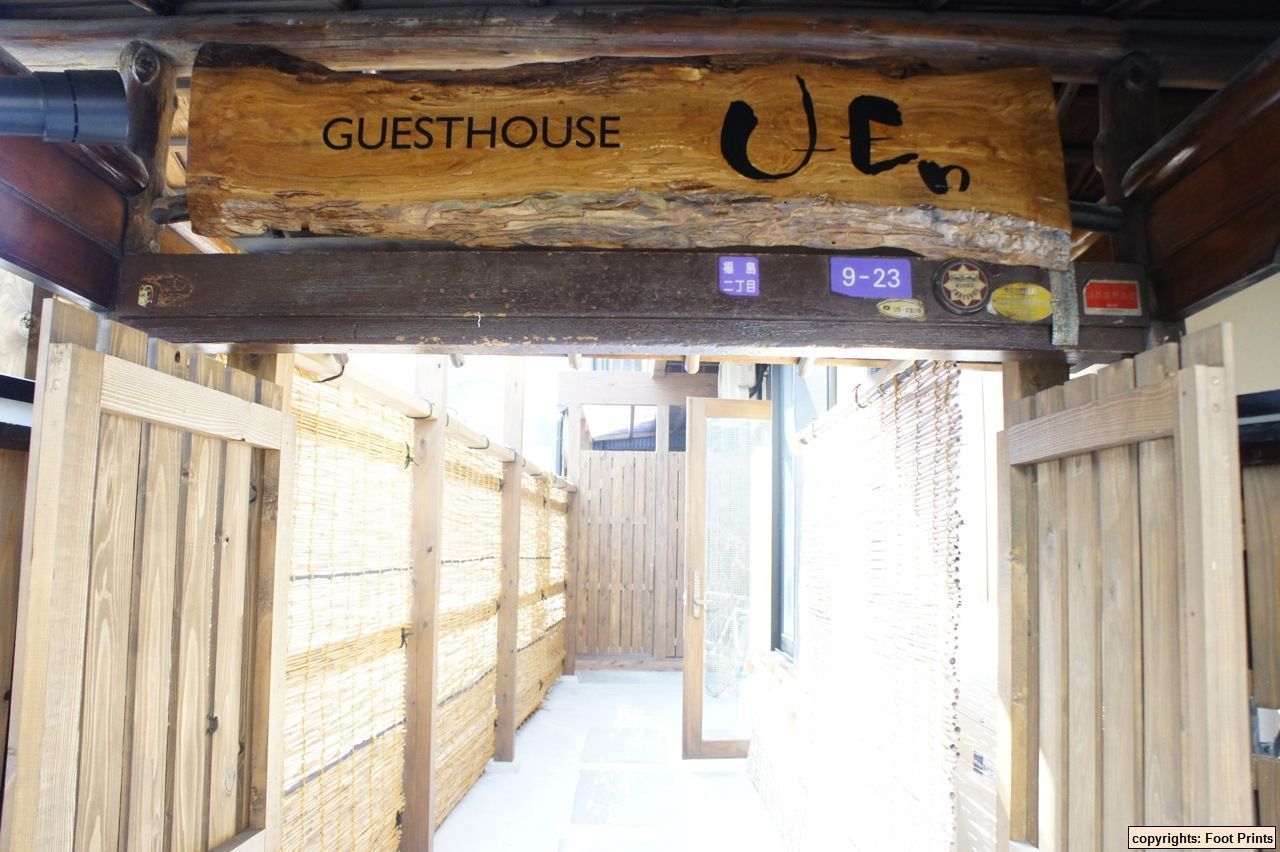 A wooden guesthouse entrance with a sign reading "GUESTHOUSE" and a license plate number "9-23".