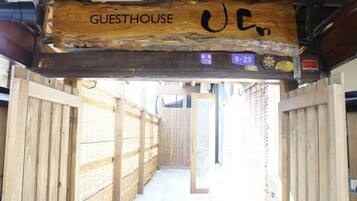A wooden guesthouse entrance with a sign reading "GUESTHOUSE" and a license plate number "9-23".
