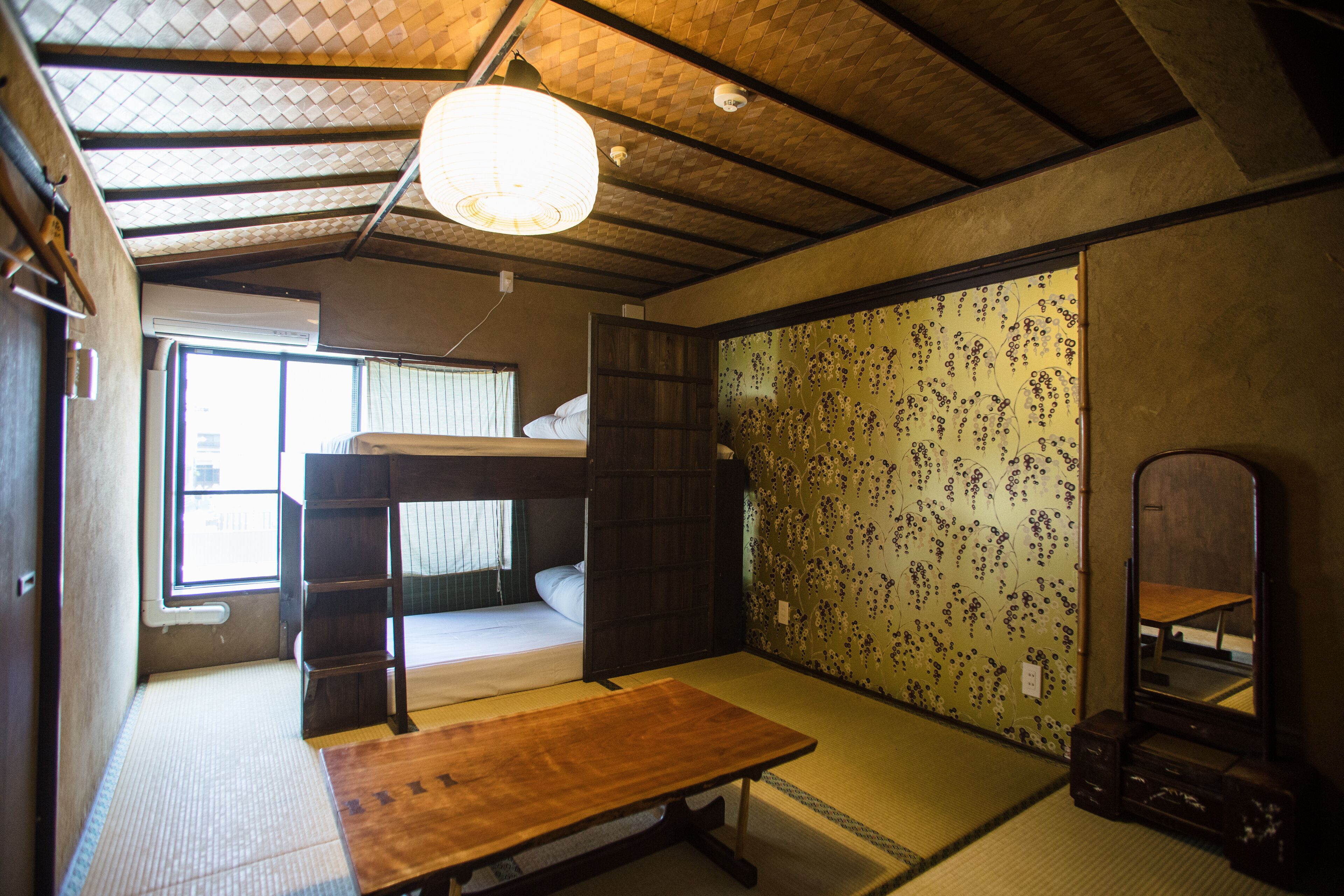 A traditional Japanese room with tatami flooring, a bunk bed, a wooden table, and a shoji screen.