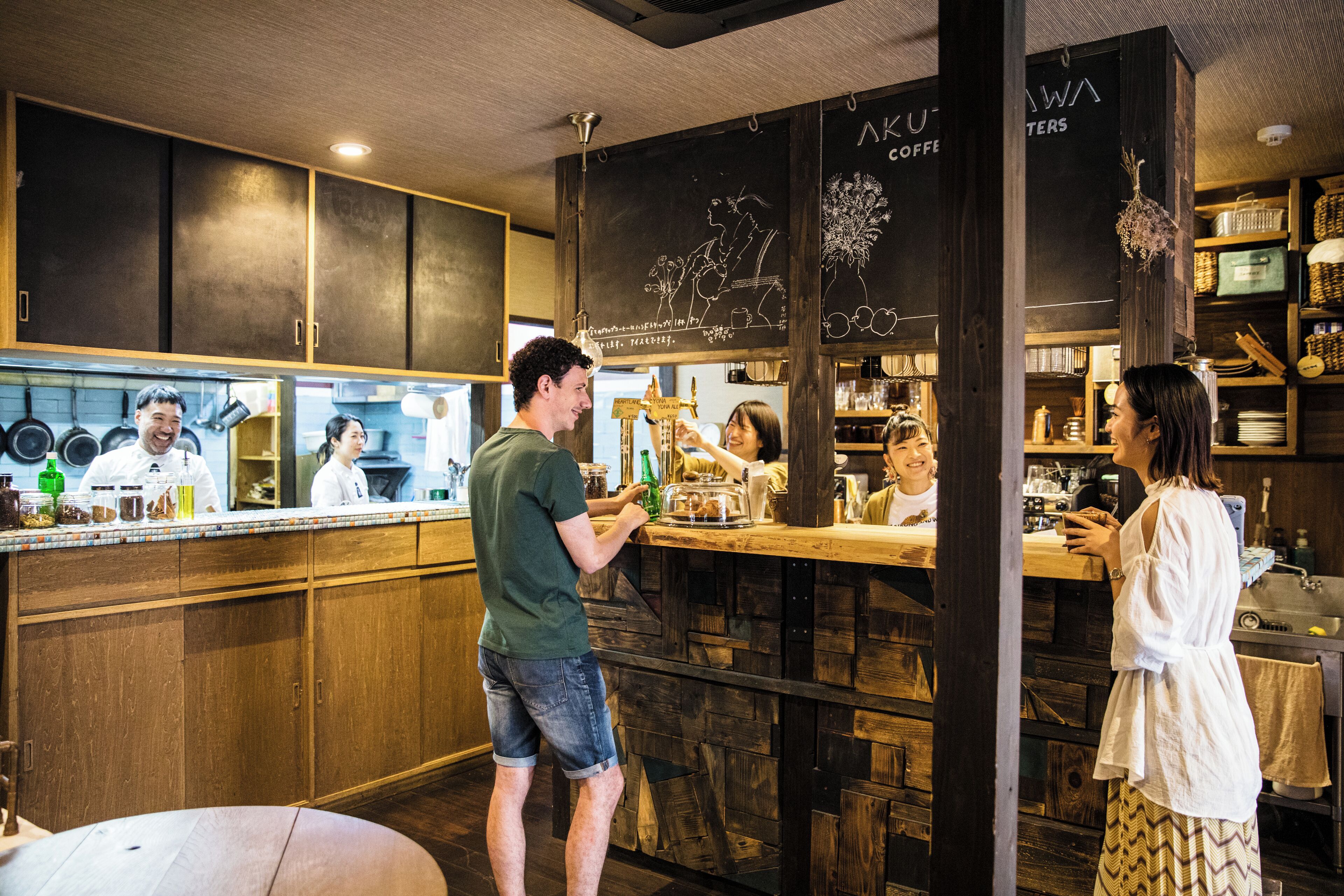 A bar area with wooden cabinets, a chalkboard menu, and a counter where a customer is ordering.