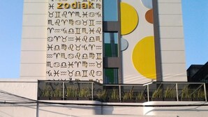 Ein Gebäude mit einem großen Tierkreiszeichen an der Fassade und der Schriftzug "ZODIAK" gut sichtbar.